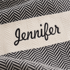 Close-up of Jennifer embroidery on a black herringbone towel